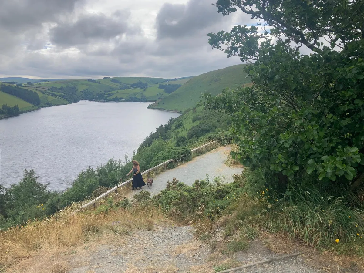 Zoe Spencer walking her dog beside a reservoir in the Mid-Wales hills